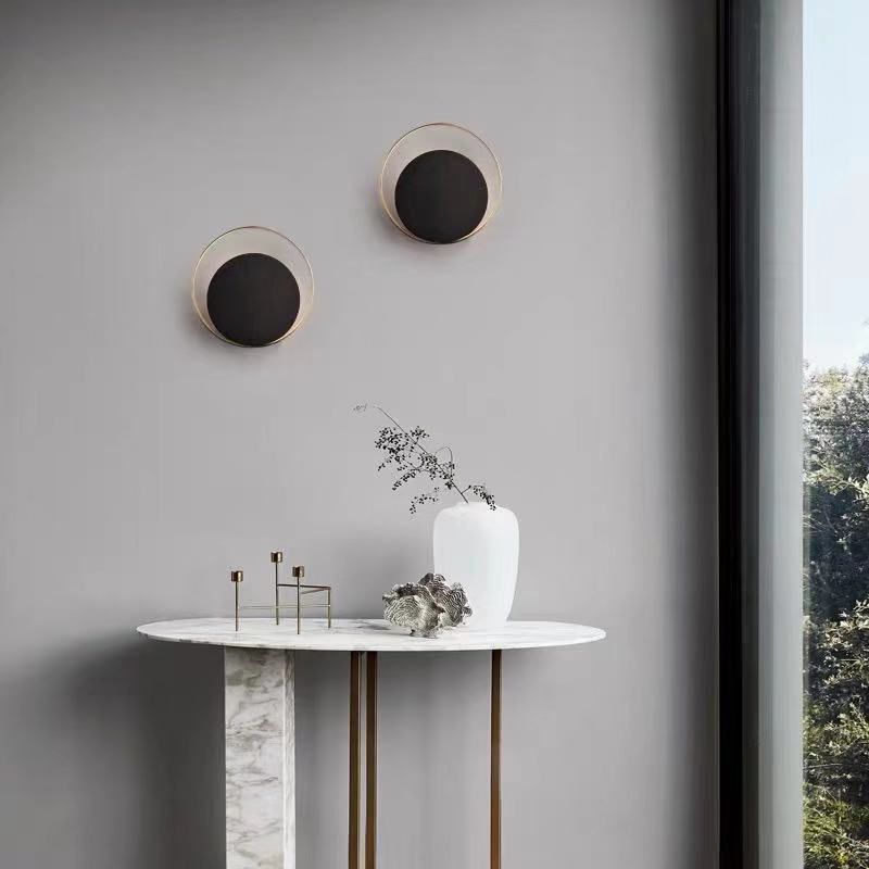 Lampada a parete circolare nera e oro nella moderna semplicità della parete in ferro battuto per gli spazi interni