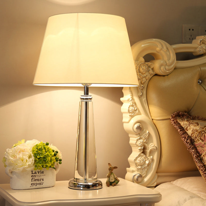 Lámpara de mesa cónica de tela estilo rural luz nocturna de dormitorio de un solo cabezal en color beige con base de cristal