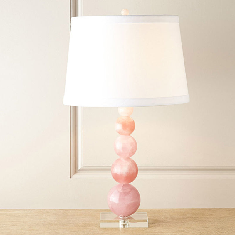 Lampada da comodino con paralume a botte Lampada da comodino bianca singola in tessuto modernista con supporto in vetro rosa con sfere