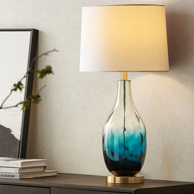 Lámpara de tela contemporánea de beige/marrón 1 cabezal iluminación de mesa de tambor contemporánea con base de vidrio azul que se desvanece del frasco