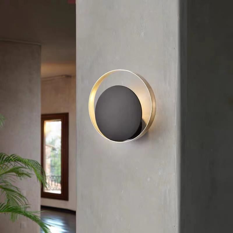 Lampada a parete circolare nera e oro nella moderna semplicità della parete in ferro battuto per gli spazi interni